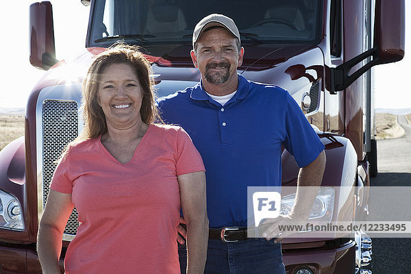 Portrait of a Caucasian husband and wife driving team with their commercial truck.