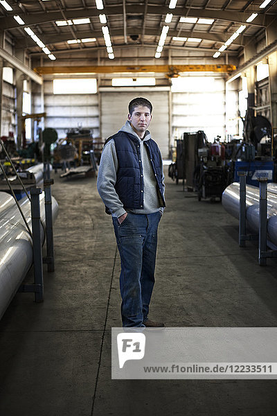 Young Caucasian man factory worker standing in a sheet metal factory.