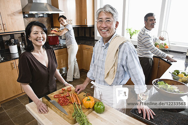 Vier Personen  zwei Paare bereiten in einer Küche eine gesunde Mahlzeit zu.