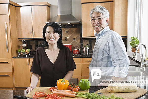 Asian man and woman preparing fresh vegetables in their kitchen.