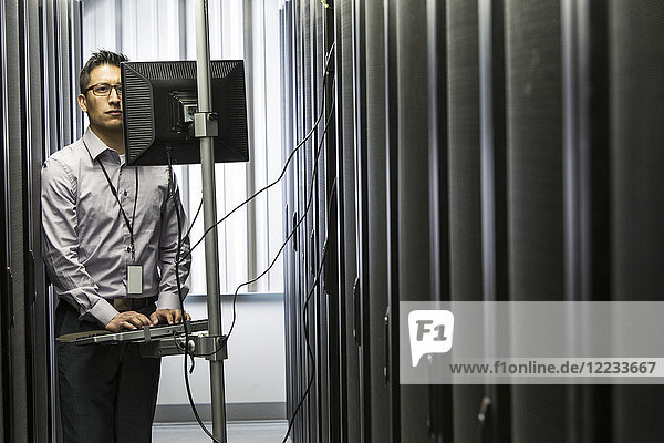 Hispanoamerikanischer Techniker  der Diagnosetests auf Computerservern in einer großen Serverfarm durchführt.