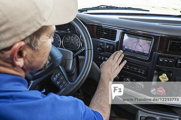 Am Straßenrand geparkter Fahrer  der ein GPS-Kartierungsgerät in der Kabine eines Lastkraftwagens benutzt.