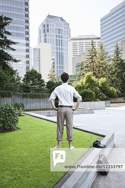Businessman taking a break standing barefoot in a downtown city park.