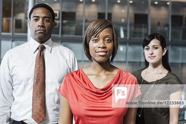 Mixed race team of business people in the lobby of a large office building.