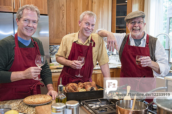 Drei befreundete ältere Männer kochen in der Küche eine Mahlzeit.