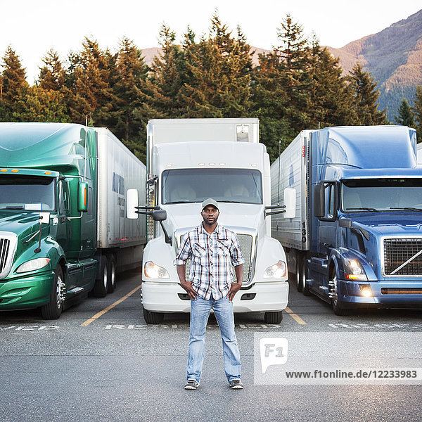 Black man truck driver near his truck parked in a parking lot at a truck stop