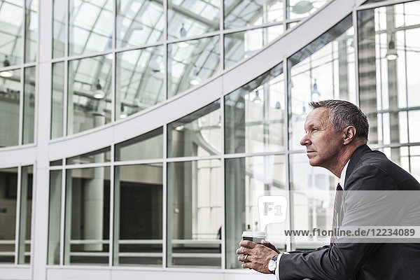 Caucasian businessman looking from a balcony near a covered walkway.