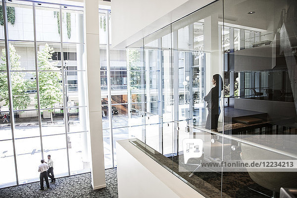 Geschäftsfrau  die am Fenster eines Konferenzraumes in einem großen Geschäftszentrum steht.