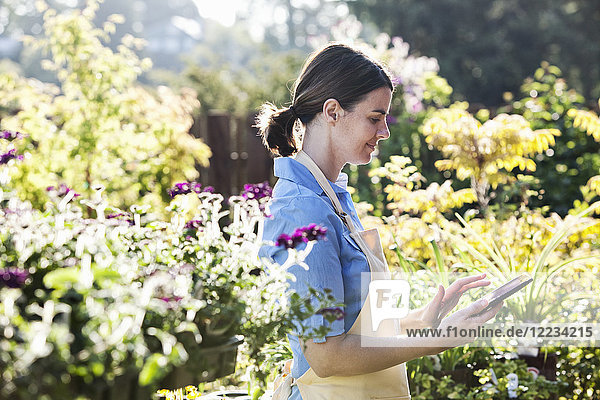 Kaukasische Angestellte einer Gärtnerei in einem Gartenzentrum  die eine Bestellung für neue Pflanzen verfasst.
