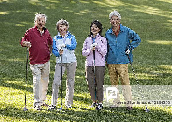 Two young senior golfing couples on the course and ready to play.