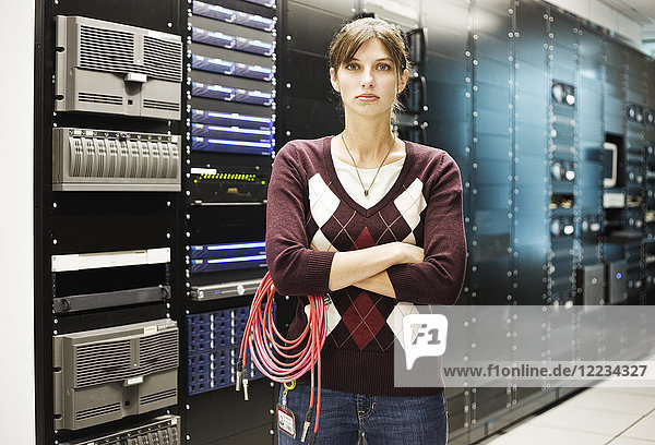 Porträt einer Technikerin  die in einem großen Computer-Serverraum arbeitet.