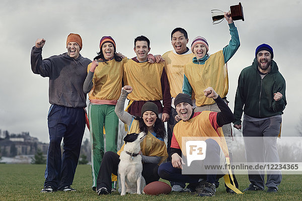 Teammitglieder  die im Winter bei einer Sportveranstaltung im Freien einen Sieg und eine Trophäe feiern.