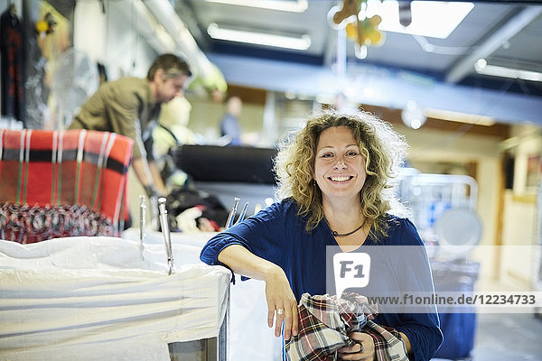 Porträt eines lächelnden blonden  reifen Arbeiters am Tisch in der Werkstatt