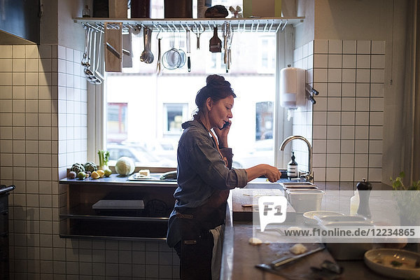 Seitenansicht des reifen Küchenchefs beim Zubereiten von Speisen in der Restaurantküche.