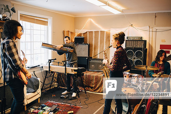 Männliche und weibliche Freunde spielen verschiedene Instrumente im Tonstudio.