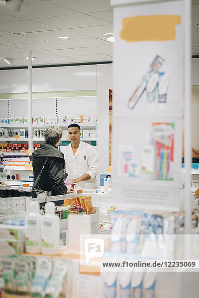 Senior Kundin im Gespräch mit Apothekerin an der Kasse im Geschäft