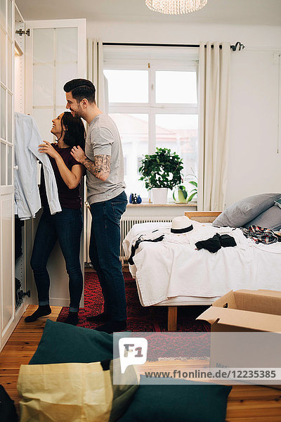 Mann und Frau beim Zusammenstellen der Kleidung im Schrank im neuen Zuhause