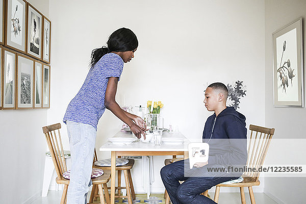 Mother serving food for son at dining table in house