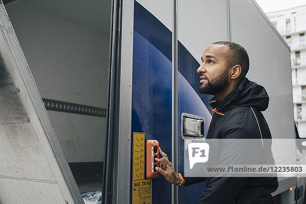 Zuversichtlicher männlicher Arbeiter drückt den Knopf am Lieferwagen in der Stadt