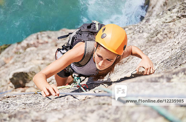 Focused  determined female rock climber scaling rock