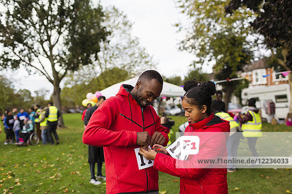 Tochter pinnt Marathon-Lätzchen auf Vater Läufer beim Benefizlauf im Park