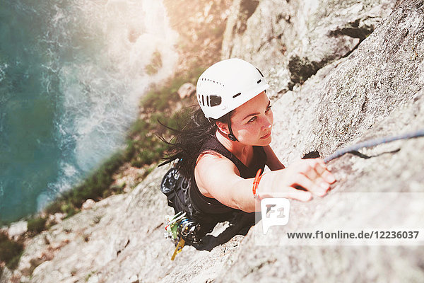 Focused  determined female rock climber scaling rock