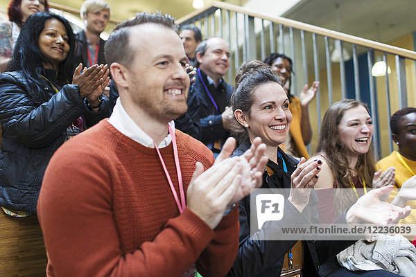 Smiling conference audience clapping