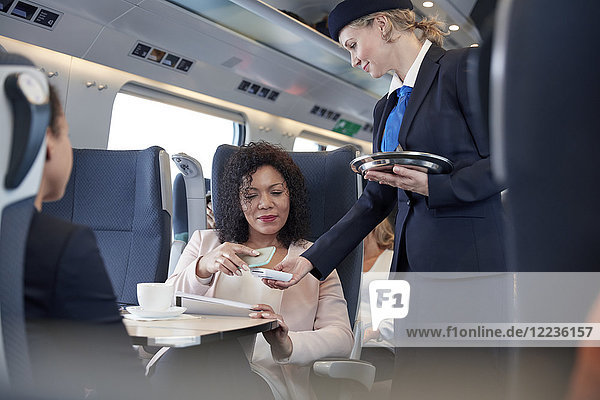 Geschäftsfrau mit Smartphone über kontaktloses Bezahlen  zahlende Begleitperson im Personenzug