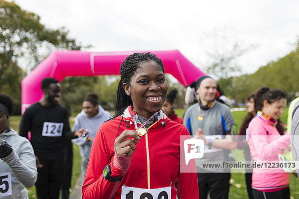 Portrait confident female runner showing medal at charity run