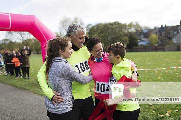 Happy family hugging at charity run in park