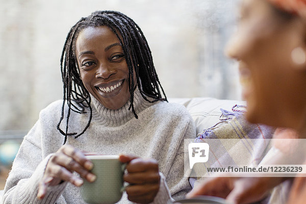 Enthusiastische  lächelnde Frau  die einem Freund zuhört und Kaffee trinkt.