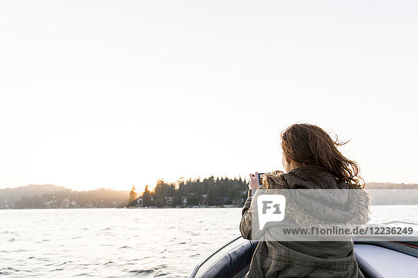 Frau mit Fotohandy  fotografiert ruhigen See