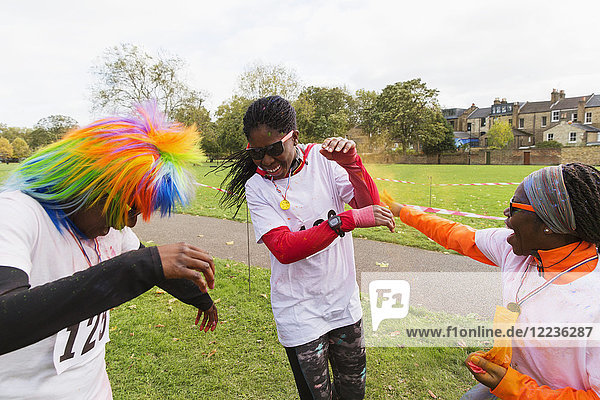 Playful runners celebrating  throwing holi powder at charity run in park