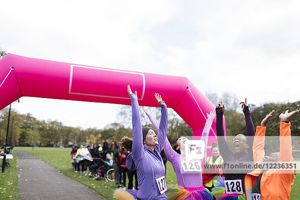 Enthusiastic female runners in tutus cheering  celebrating at charity run finish line