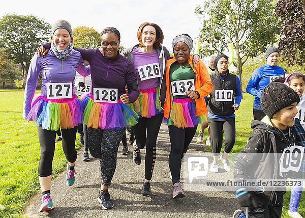 Smiling female runners in tutus walking at charity run in park