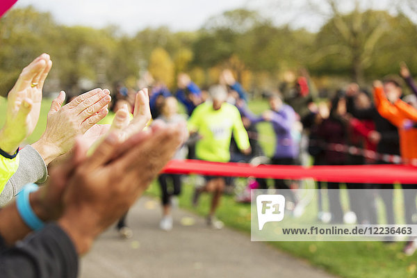 Spectators clapping for runners nearing finish line at charity event