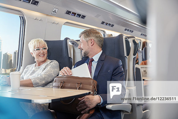 Businessman and businesswoman working  talking on passenger train