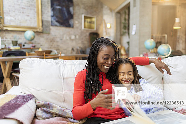 Mother and daughter looking at photo album on sofa