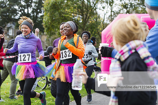Female runners in tutus running at charity race in park