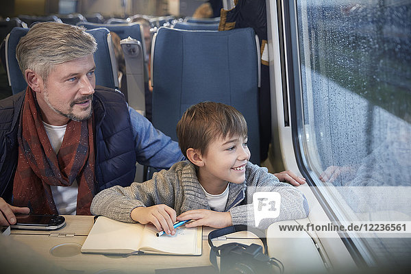 Vater und Sohn schauen aus dem Fenster im Personenzug
