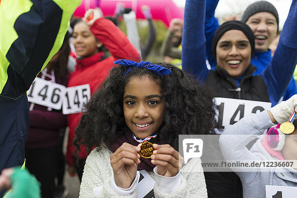 Portrait smiling girl runner showing medal at charity run in park