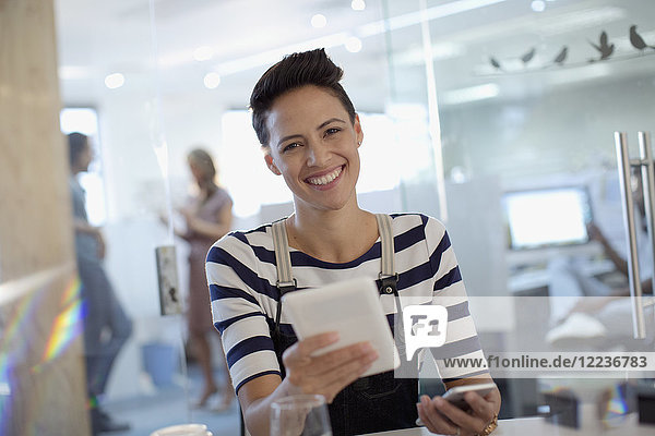 Porträt einer lächelnden  selbstbewussten  kreativen Geschäftsfrau  die ein digitales Tablet im Büro benutzt