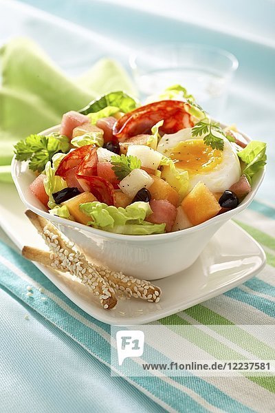 Salat mit Salami  einem halben Ei  Melone und Oliven