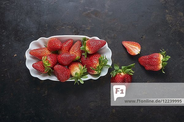 Frische Erdbeeren in einer weißen Schale auf einer schwarzen Metallfläche