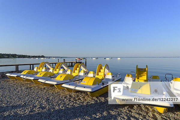 Eine Reihe bunter Tretboote am morgendlichen Strand des Gardasees (Lago di Garda) in Bardolino in Venetien  Italien