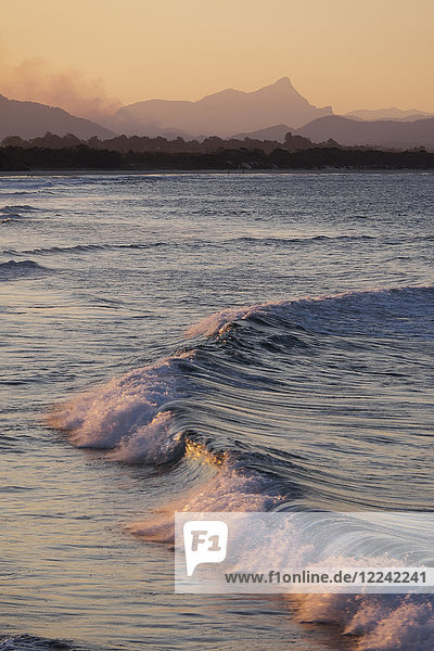 Pastellfarbene Wellen  die bei Sonnenuntergang am Strand von Byron Bay in New South Wales  Australien  auf die Uferlinie treffen