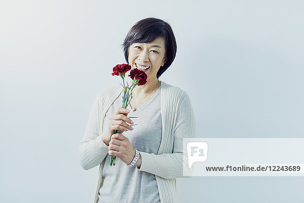Japanische ältere Frau hält rote Rosen