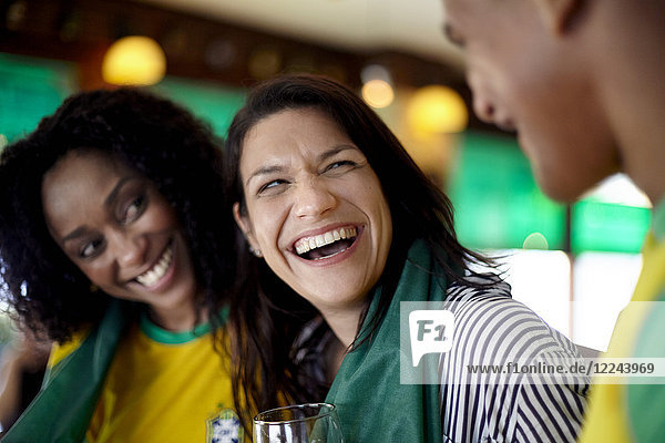 Frau lacht in der Bar mit Freunden
