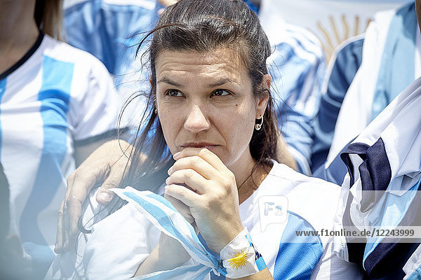 Argentinian football fan watching match with anxious expression on face