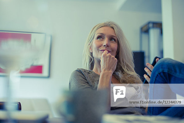 Reife Frau mit Smartphone zu Hause